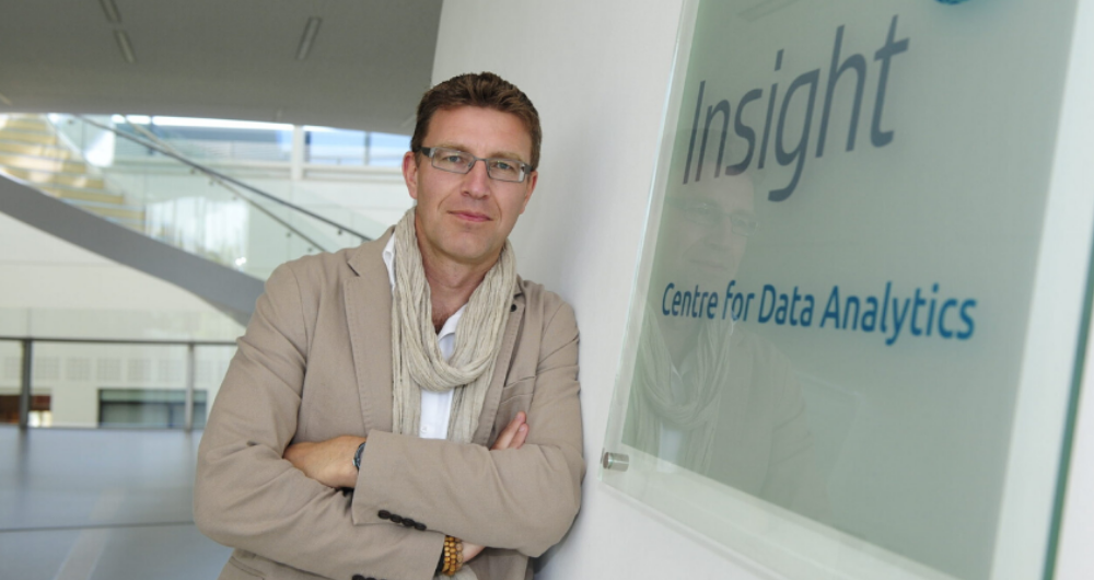 Prof Barry Smyth standing beside Insight logo