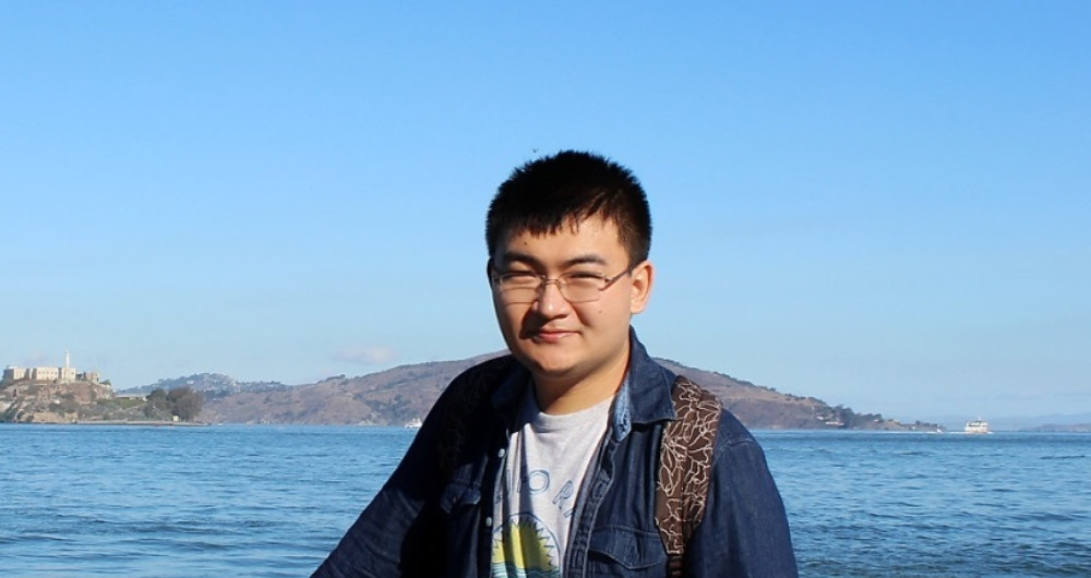 Mingming Liu of DCU standing at a wooden fence with the ocean in the background