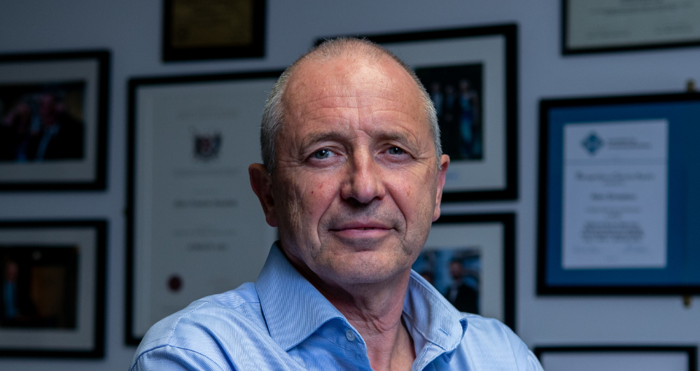 Professor Alan meaton of DCU standing against a wall with framed photos and diplomas